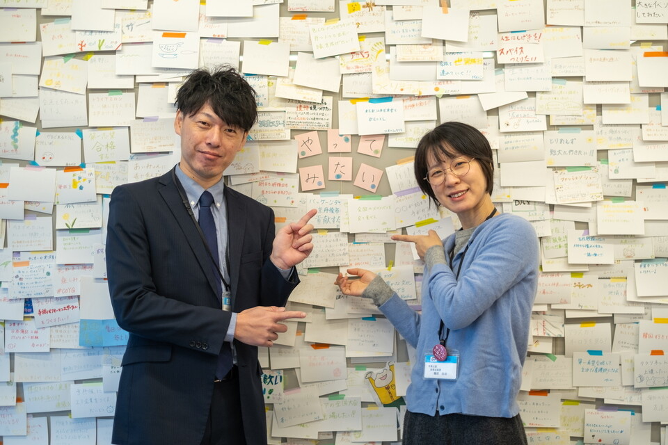 壁を埋め尽くす「やってみたいこと」を前に事業への思いを話す篠原さんと増馬さん